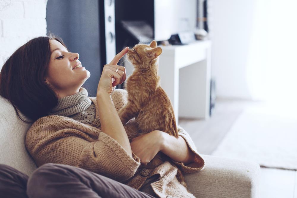 woman cuddling cat in the sofa