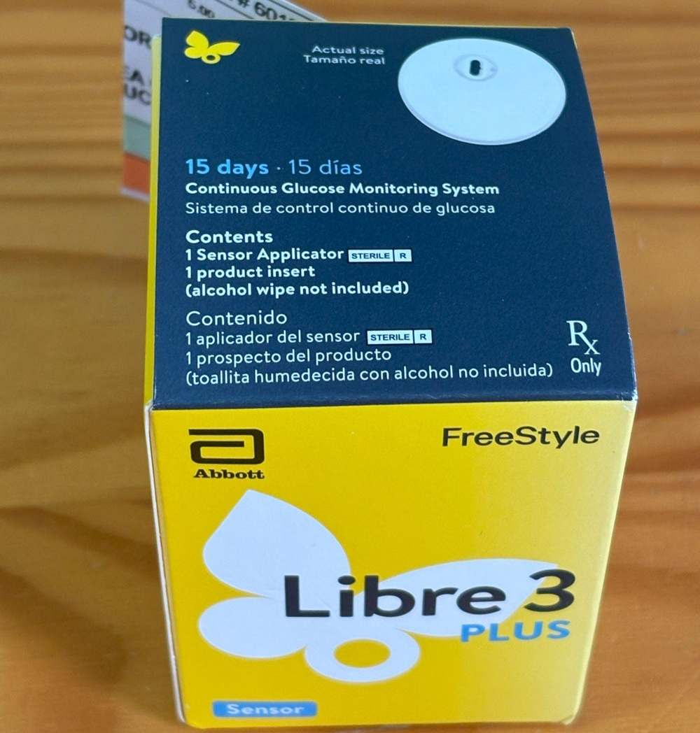 FreeStyle Libre Plus Continuous Glucose Monitoring System box on a wood table.