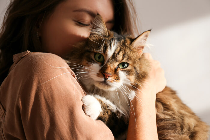 Woman holding and tenderly hugging her beloved cat
