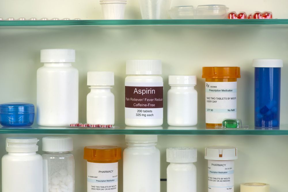 Medicine cabinet with an aspirin bottle, emphasizing the necessity of securely storing medications out of reach from pets, including cats, to prevent accidental ingestion and potential harm.