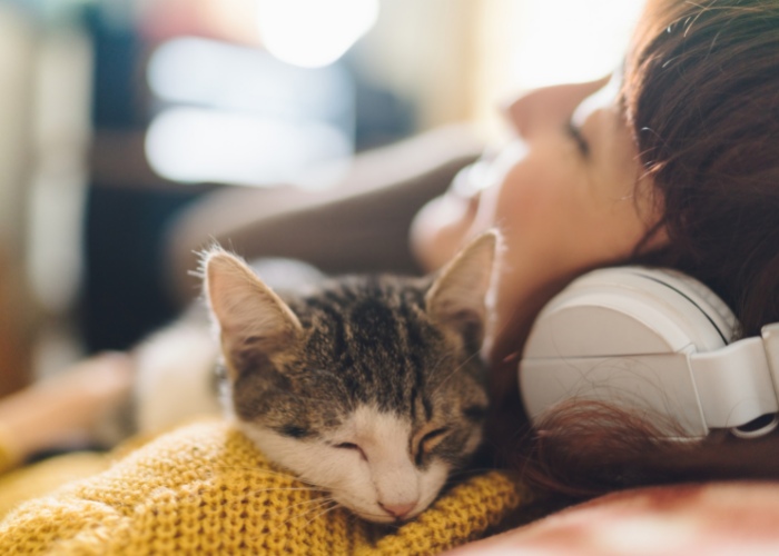 Image depicting a woman and her cat listening to music together.