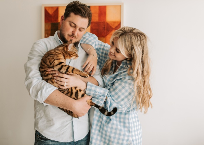 Charming picture featuring a cute couple sharing a delightful moment with their cat, portraying the joy and love that pets can bring to relationships.