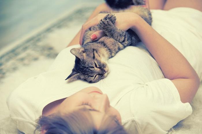 Woman sleeping with a cat draped across her chest