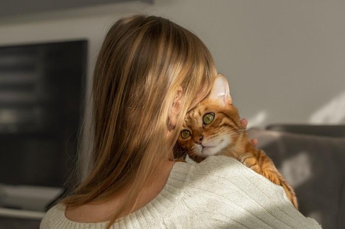 girl and her Bengal cat press their heads together