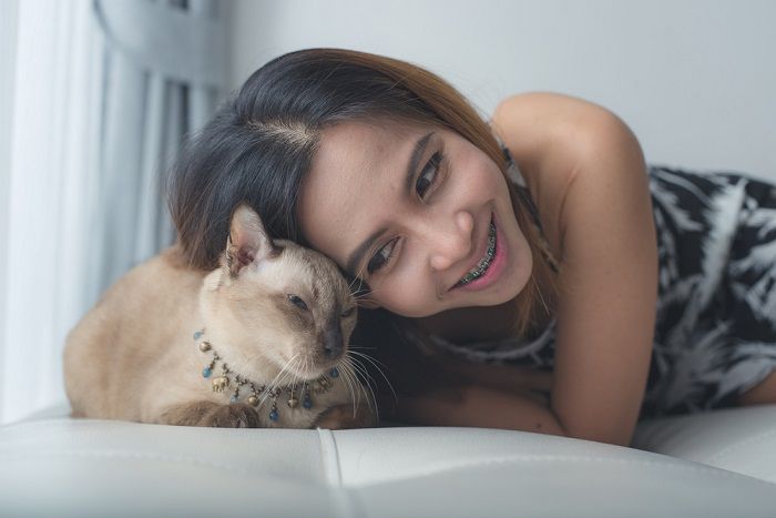 woman and cat laying on sofa