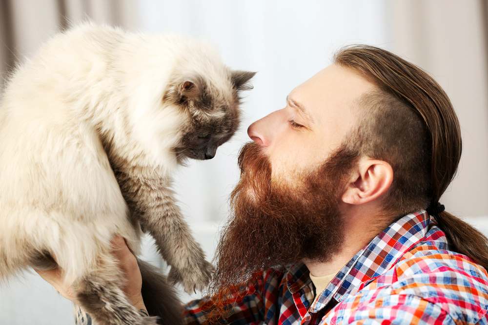 Joven barbudo con gato esponjoso
