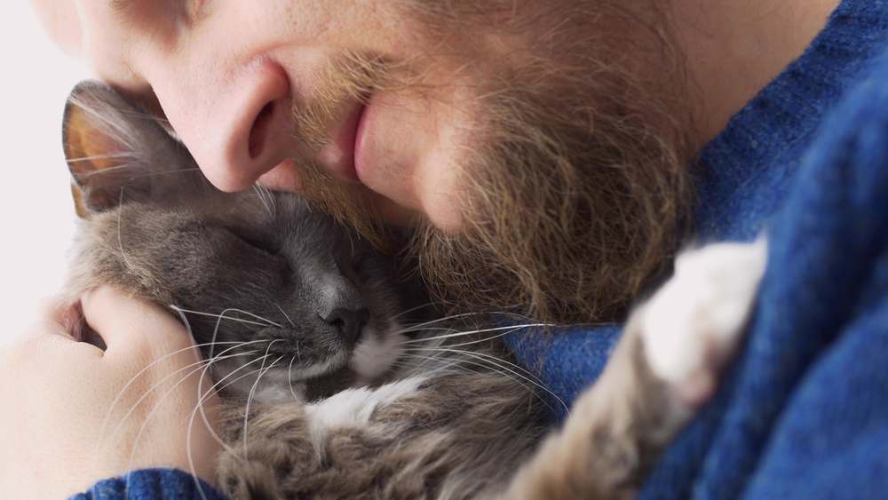 bearded man lovingly hugs his cat