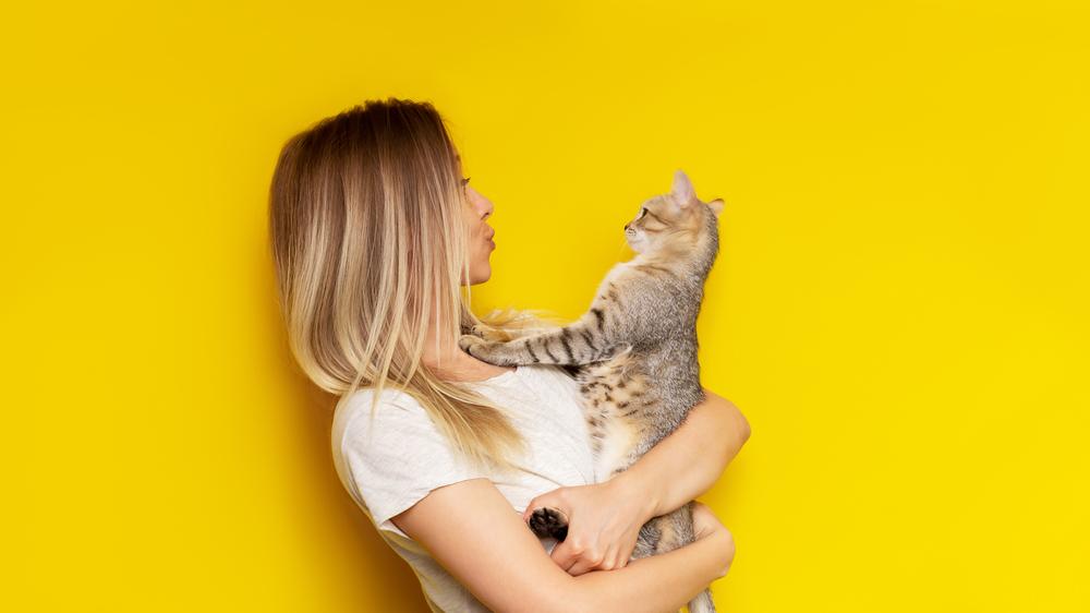 woman holds a tabby cat in her hands
