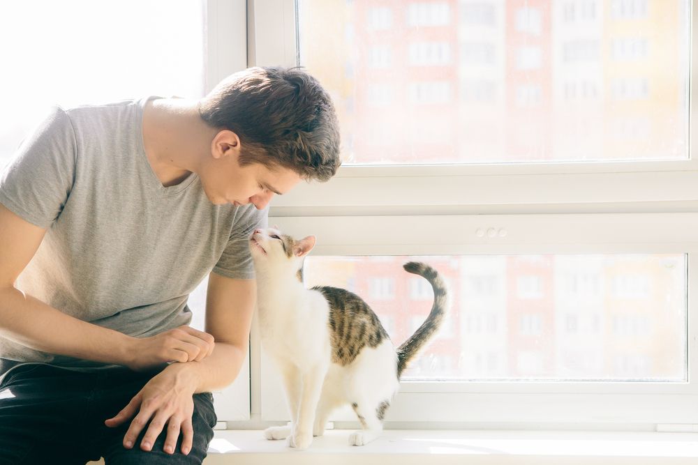 young man is sitting with a cat