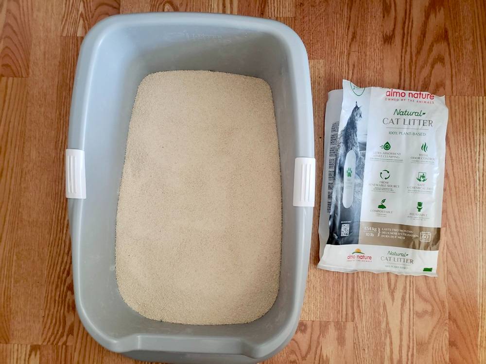 Bag of Almo Nature Natural Cat Litter next to a filled litter box