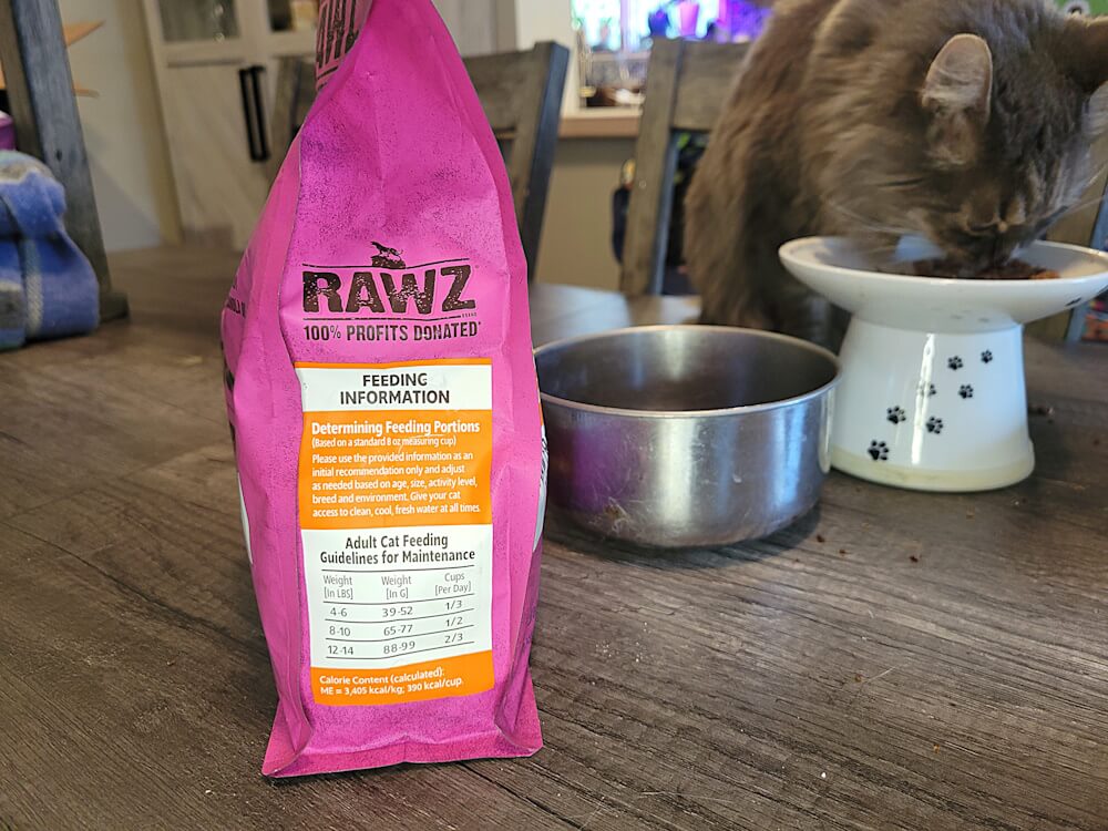 hand holding a small amount of dry food above a bag of cat food