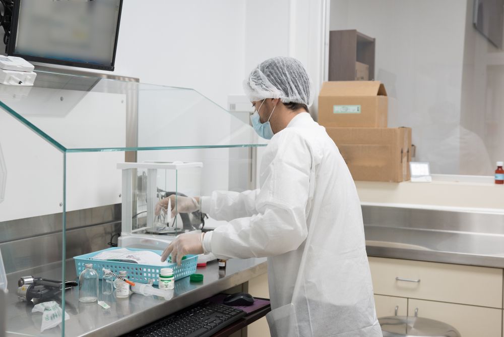 compounding pharmacist makes a compounded preparation in a chemical fume hood