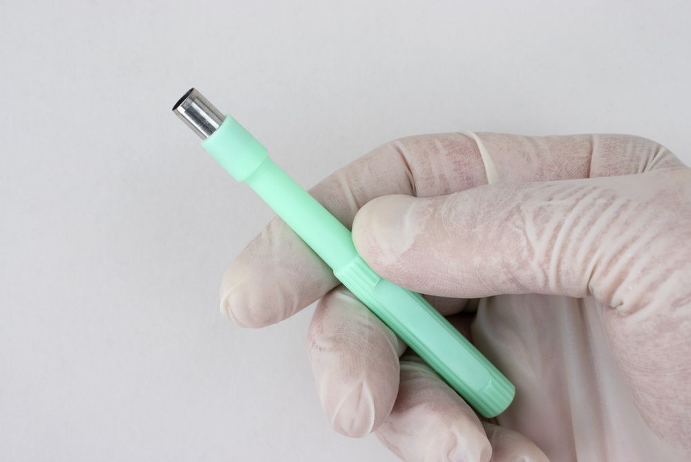 Close up photo of a mint green biopsy punch instrument.